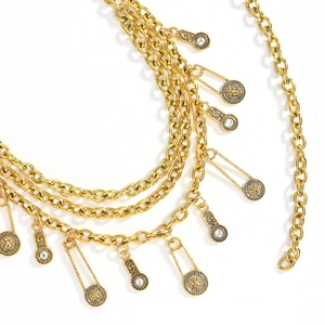 Macro detail of multi-layer golden chain belt featuring lion head coins and safety pin charms