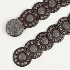Detail van een boheemse donkerbruine leren riem met vintage metalen bloemmotieven en studs