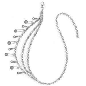 Detail of silver punk layered waist chain with metal pins and vintage embossed charms
