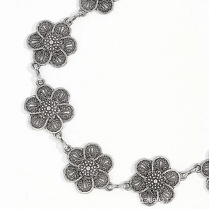 Detail of vintage silver flower waist chain links with textured petals on white background