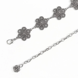 Detail of vintage silver flower waist chain featuring embossed petals and lobster clasp