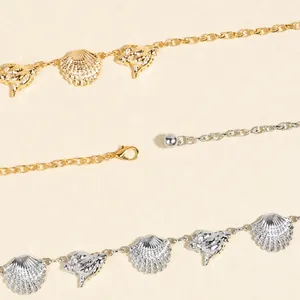 Detail view of gold and silver bohemian waist chains with shell and dolphin charms