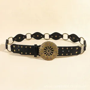 Detail of vintage western belt with carved metal sunflower buckle and studded leather rings