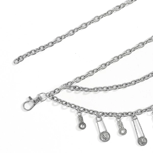 Detail of vintage silver chain belt featuring lion head medallion and safety pin charms