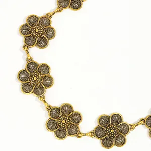 Detail of vintage gold flower waist chain with textured petals and bohemian aesthetic