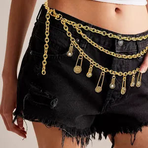 Macro shot of gold multi-layer waist chain with vintage coin charms and pins on black jeans