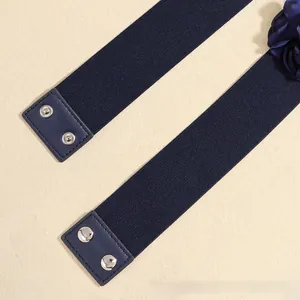 Macro shot of navy elastic waist belt featuring a fabric flower and silver snap button