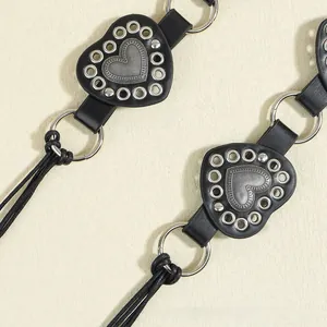 Detail of punk style black leather belt featuring silver heart studs and metal ring accents