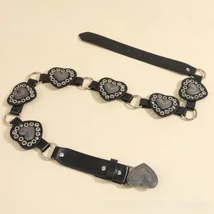 Detail of vintage black belt featuring silver metal heart plates and punk style eyelets