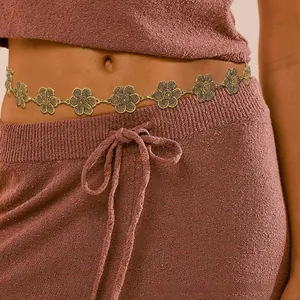 Detail of vintage gold flower chain belt styled on dark knit dress for women