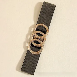 Macro detail of elastic black gold fabric belt with three interlocking wavy metal rings