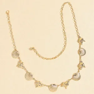 Close-up of golden shell and conch pendants on a fine bohemian style beach waist chain