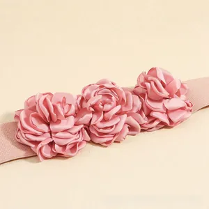 Detailed view of three dusty pink fabric roses on an elastic waist belt accessory
