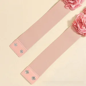 Detailed view of elastic pink belts with 3D fabric flowers and silver snap buttons