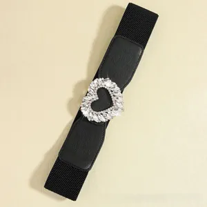 Close-up of black elastic belt featuring a sparkling heart-shaped rhinestone buckle