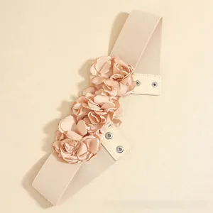 Detailed view of elastic belt featuring three fabric roses and metal snap fasteners