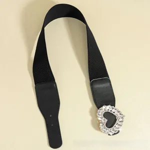 Close-up of black elastic belt featuring a sparkling heart-shaped rhinestone buckle