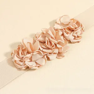 Detailed close-up of champagne elastic waist belt with triple layered fabric flowers