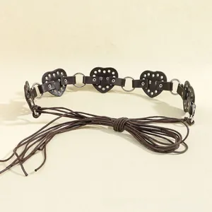 Detail of dark brown heart-shaped leather patches with silver rivets and metal ring connectors