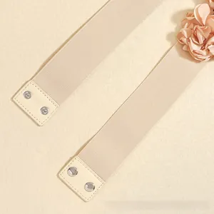 Detail of champagne elastic waist belt with fabric flower and metal snap buttons
