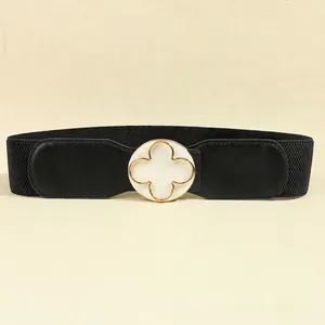 Detail of black elastic waist belt with a golden clover pattern circular buckle