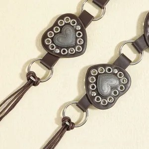 Detail of dark brown leather belt featuring heart patches, rivets, and braided cord