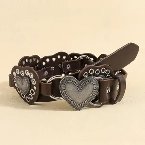 Detail of dark brown leather heart segments with silver metal eyelets and embossed buckle