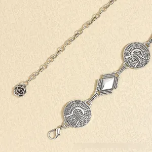 Detail of vintage metal waist chain with geometric carvings and rose flower pendant