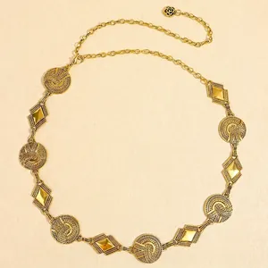 Detail view of vintage gold metal waist chain with embossed patterns and camellia charm