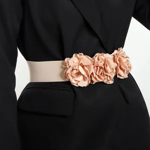 Detail of elegant elastic waist belt with three champagne 3D silk flowers on a black blazer