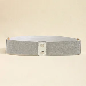 Detalle de cinturón ancho elástico gris plata con hebilla de cuero rectangular y remaches