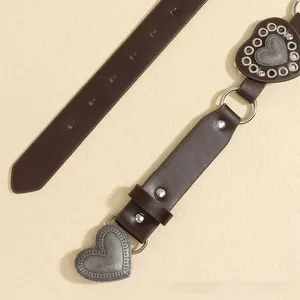 Detail of vintage brown leather belt featuring embossed silver heart buckles and metal rings