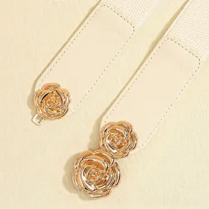 Detail der eleganten goldenen Rosenschnalle am beigefarbenen elastischen Taillengürtel