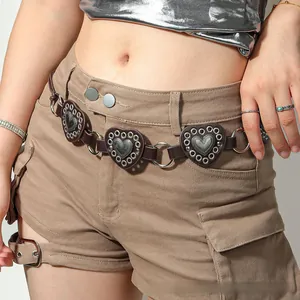Close-up of vintage heart-shaped leather charms with metal rivets on a stylish waist belt