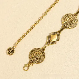 Detailed macro view of vintage gold waist chain featuring a delicate rose pendant and lobster clasp