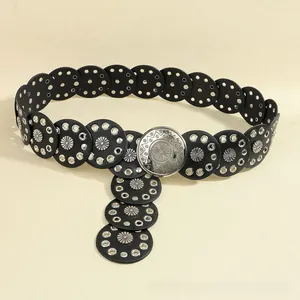 Detail of bohemian leather belt featuring silver sunburst buckle and metal studs