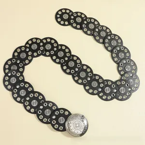 Close-up of bohemian belt featuring black circular patches with vintage metal floral accents