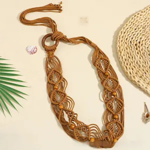 Détail d'une ceinture tressée bohème avec perles en bois sur fond de sable estival