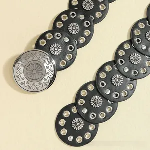 Detail of bohemian black leather belt featuring silver daisy rivets and sunburst buckle