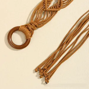 Détail d'une ceinture tressée bohème avec boucle ronde en bois et bouts à glands