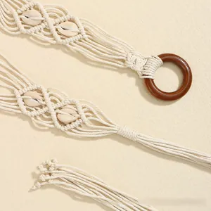 Détail d'une ceinture bohème tressée avec accents de coquillages et boucle ronde en bois