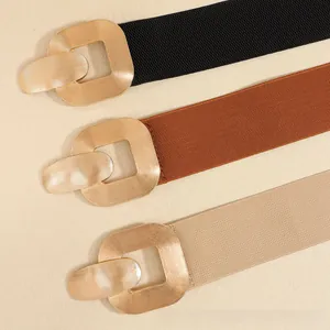 Three elastic waist belts in black, brown, and beige with golden geometric buckles