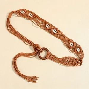 Détail d'une ceinture bohème tressée avec coquillages blancs et boucle en bois