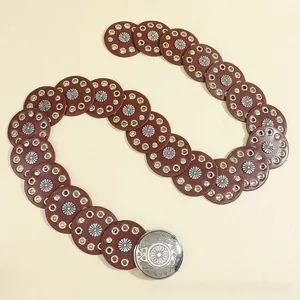 Close-up of bohemian leather belt with silver sunburst buckle and metal rivets