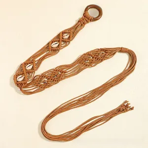 Détail de ceinture tressée bohème avec des coquillages et boucle ronde en bois foncé
