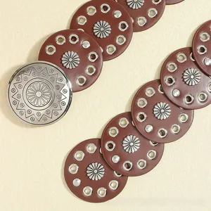 Detail of vintage bohemian belt with brown leather circles and silver sunburst buckle