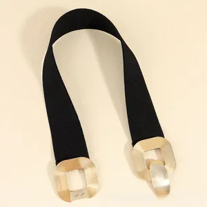 Close-up of gold geometric interlocking buckle with brushed texture on elastic belt