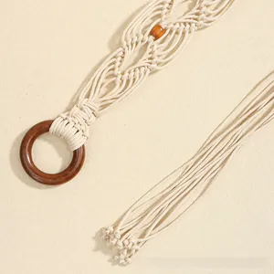 Détail d'une ceinture bohème en coton tissé avec anneau en bois, perles et longues franges