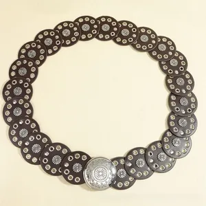 Detailed macro view of vintage bohemian belt with daisy metal studs and carved silver buckle