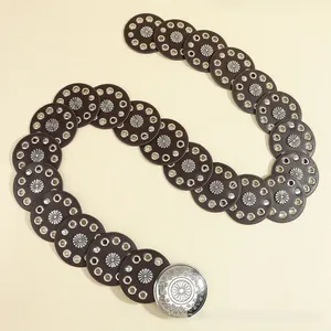 Close-up of bohemian leather belt with metal eyelets and sunflower embossed buckle